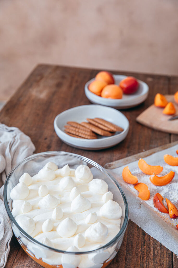 Tiramisu spéculoos abricots frais servi dans un plat en verre, garni de crème mascarpone, morceaux de spéculoos et quartiers d’abricots sur une table en bois.